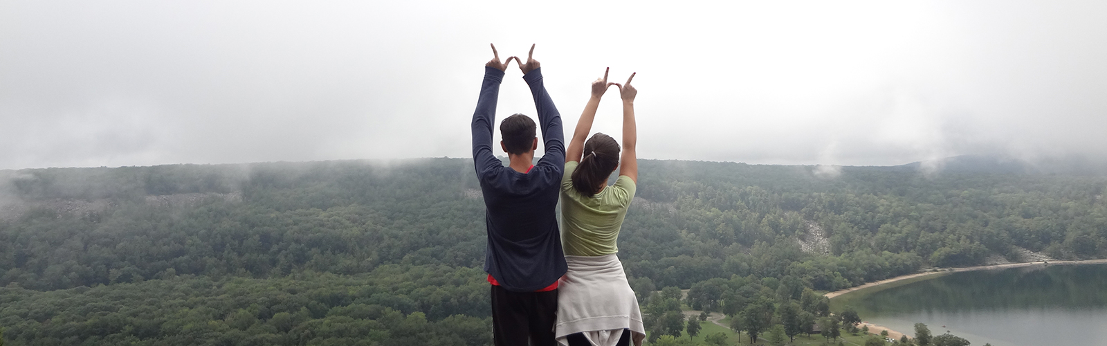 VISP students make the sign of 'W' while overlooking a scenic view.
